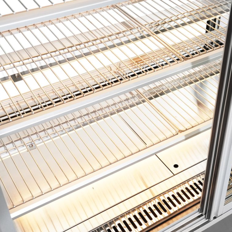 Metal wire shelves inside a refrigerator with a white interior.
