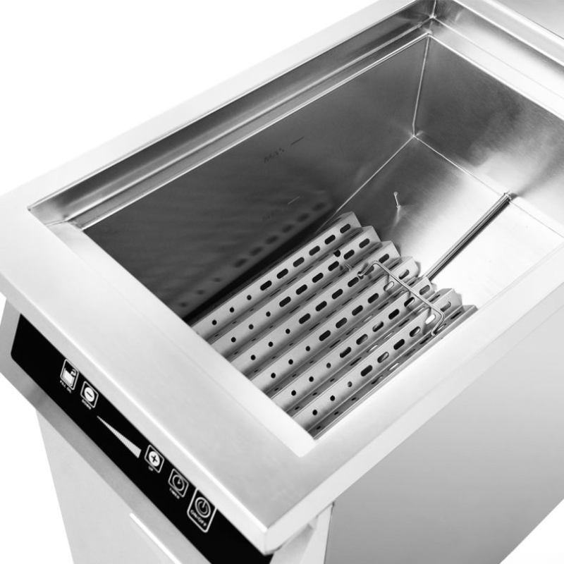 Stainless steel deep fryer with hot dogs on a white background