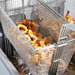 Fried calamari in a metal mesh basket over a deep fryer.