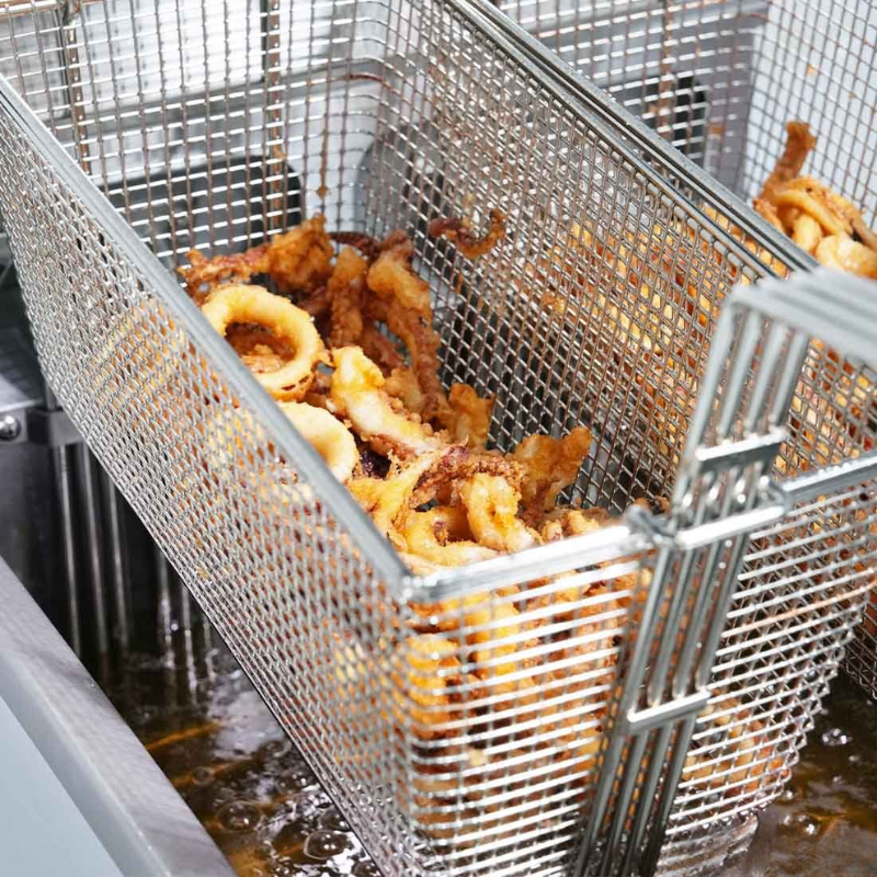 Fried calamari in a metal mesh basket over a deep fryer.