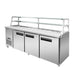 Thermaster SCB/21 stainless steel three-door sandwich bar, angled front view showing the refrigerated pan well, two-tier glass shelving above and fridge cabinet below on castors
