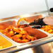 Fried chicken being served from a buffet tray with tongs and a gloved hand.