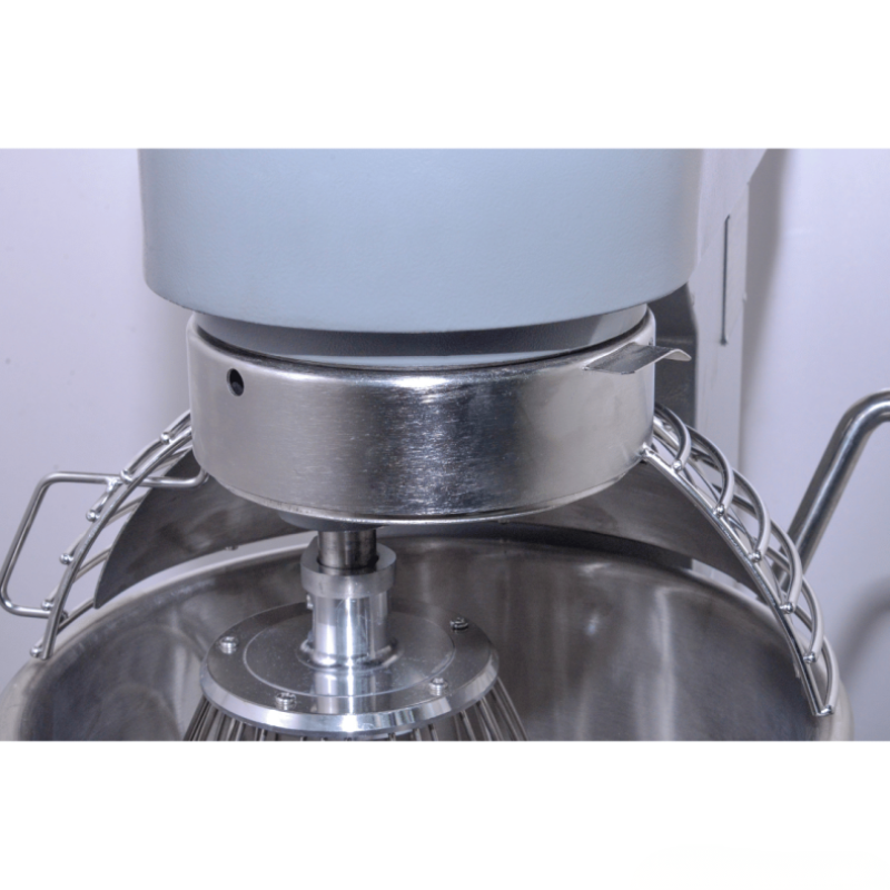 Close-up of a metal mixing bowl with a whisk attachment on a white background